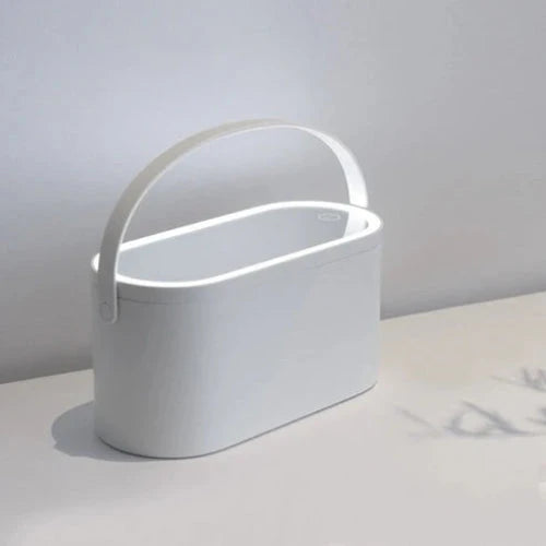 Illuminated makeup mirror box placed on vanity table, combining lighting and cosmetic storage in one.